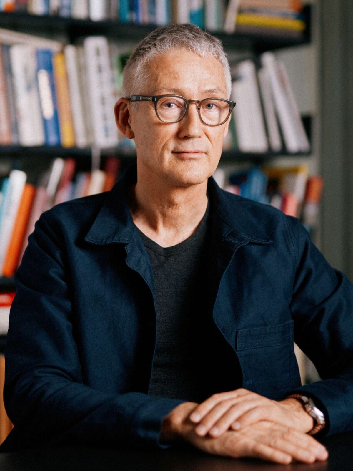 Portrett av Bård Helland foran bokhylle.