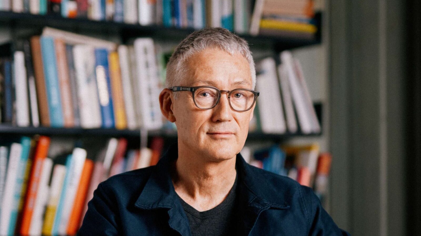 Portrett av Bård Helland foran bokhylle.
