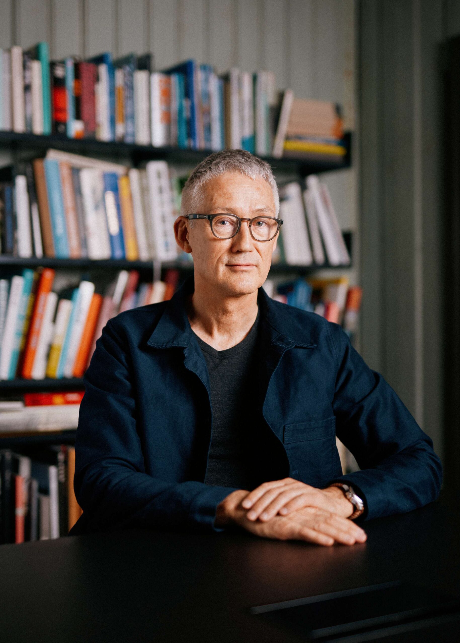 Portrett av Bård Helland foran bokhylle.