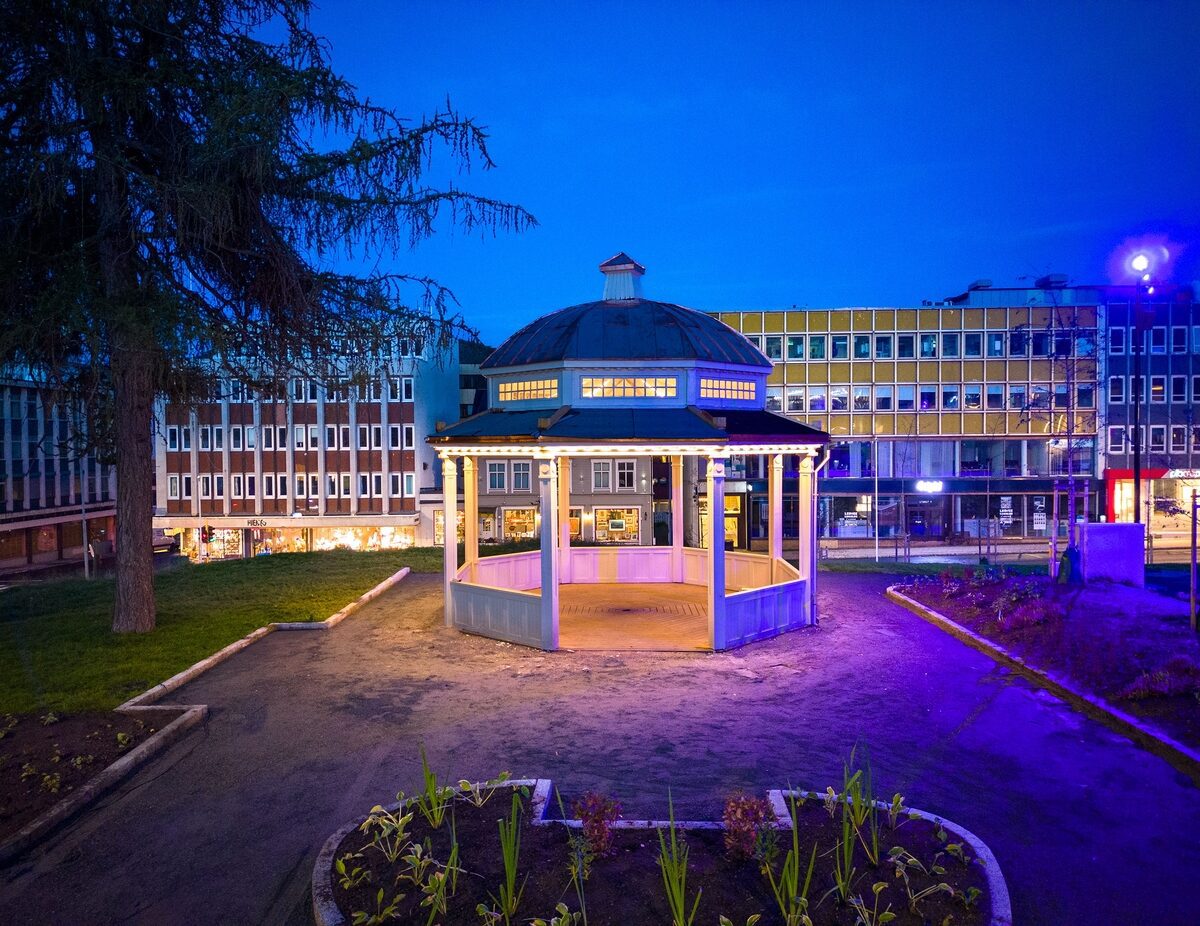 Lyssatt, åpen paviljong i park om kvelden