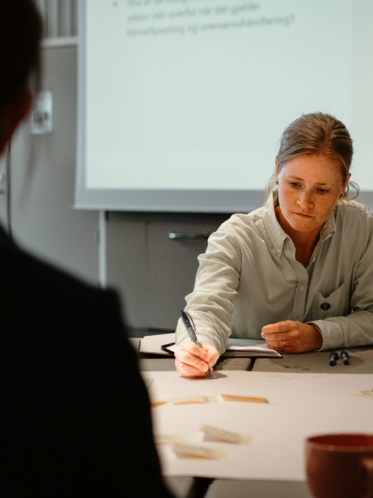 Kvinne som sitter ved et bord og skriver.