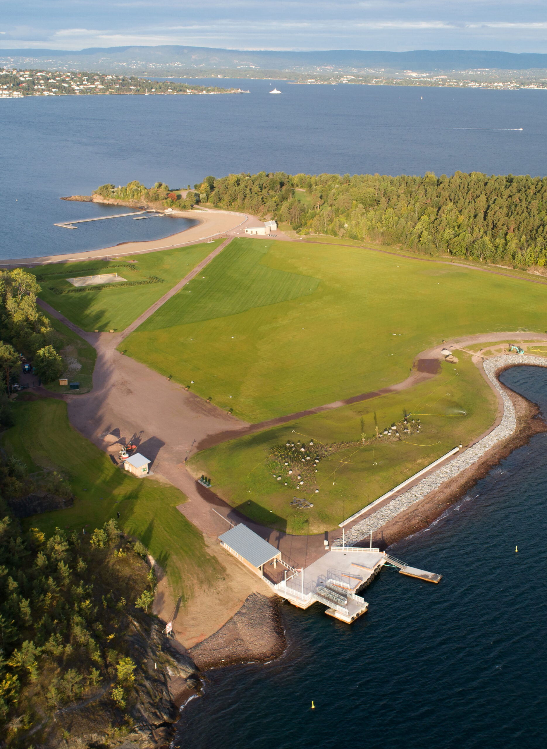 Dronebilde av den grønne sletta på Nye Langøyene med sjøen rundt.