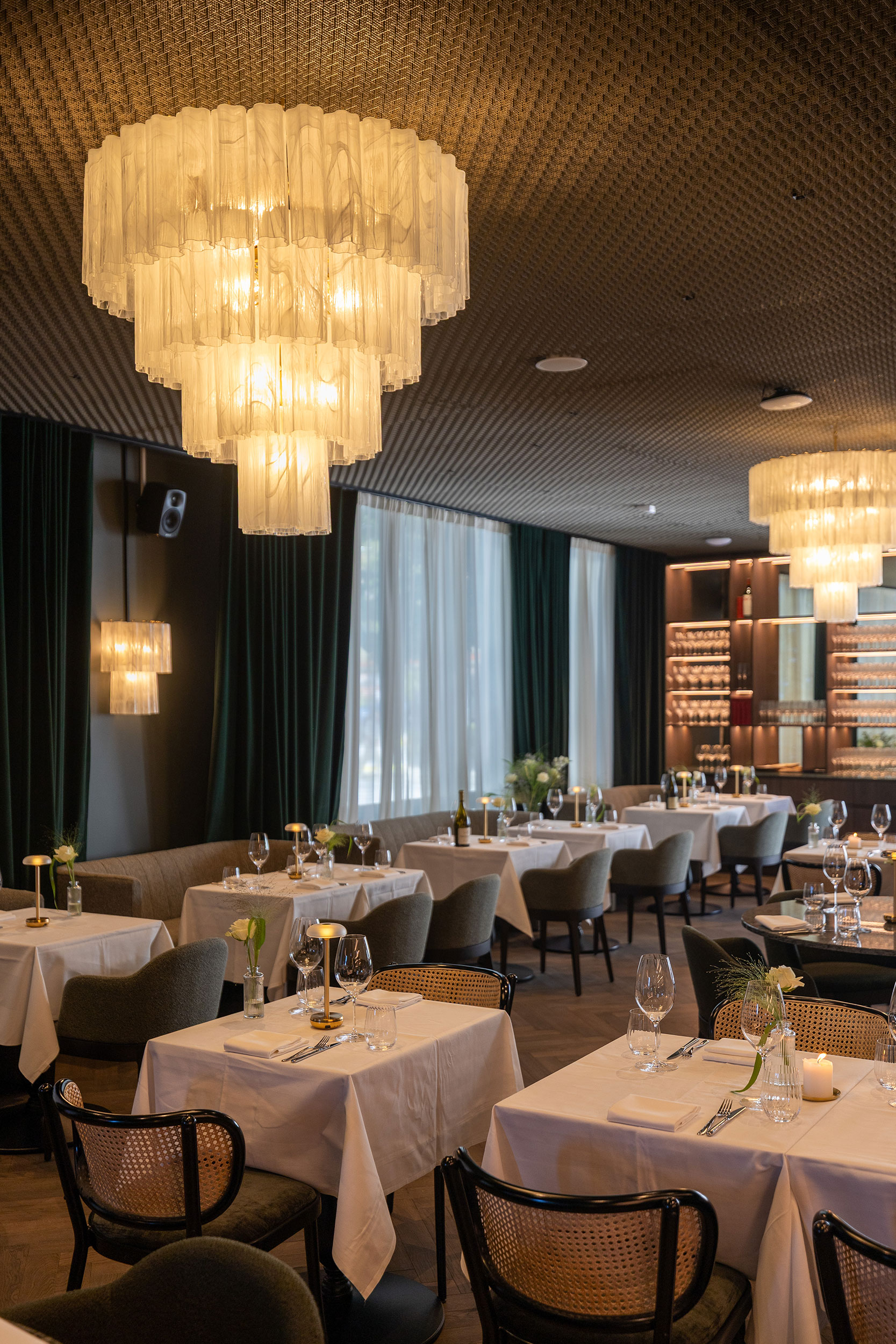 Restauranten med bord, stoler og store taklamper i SIXA, et kontorbygg som setter en ny standard for moderne arbeidsplasser.