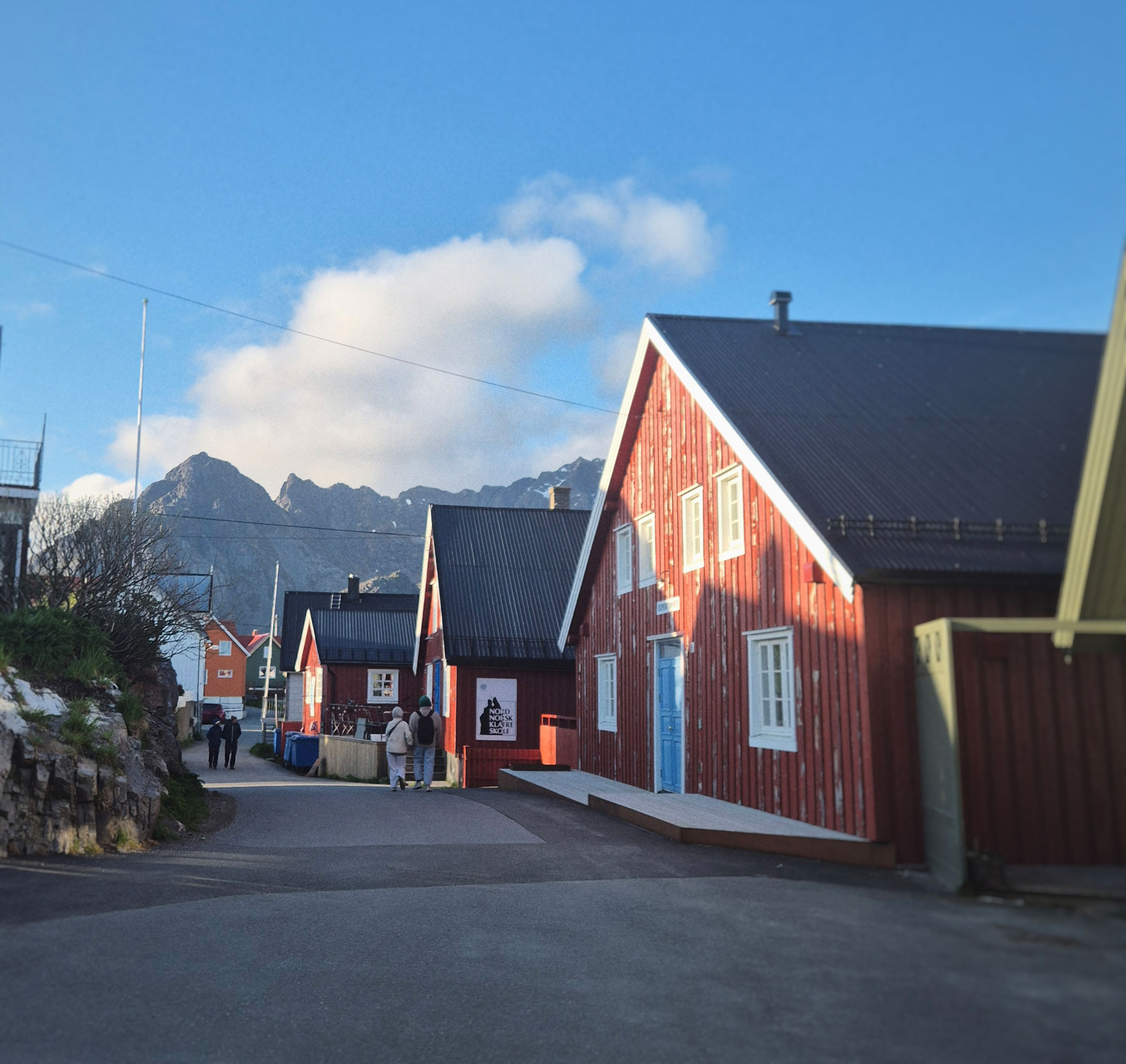 Rød trehusbebyggelse i en gate i Lofoten.