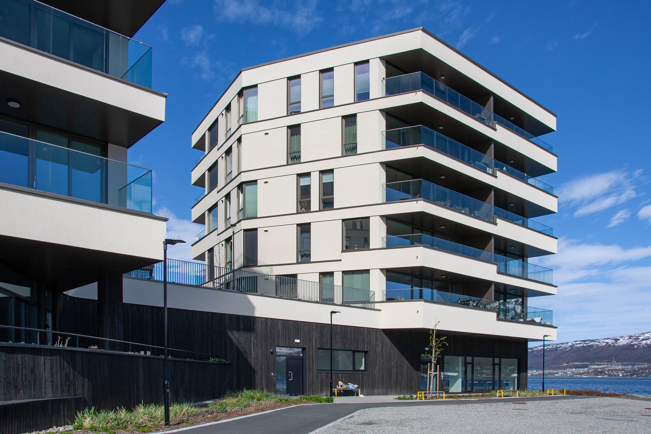 Fasaden på Alfon C med store balkonger og lysinnslipp, plassert tett ved sjøen på Kræmer Brygge.