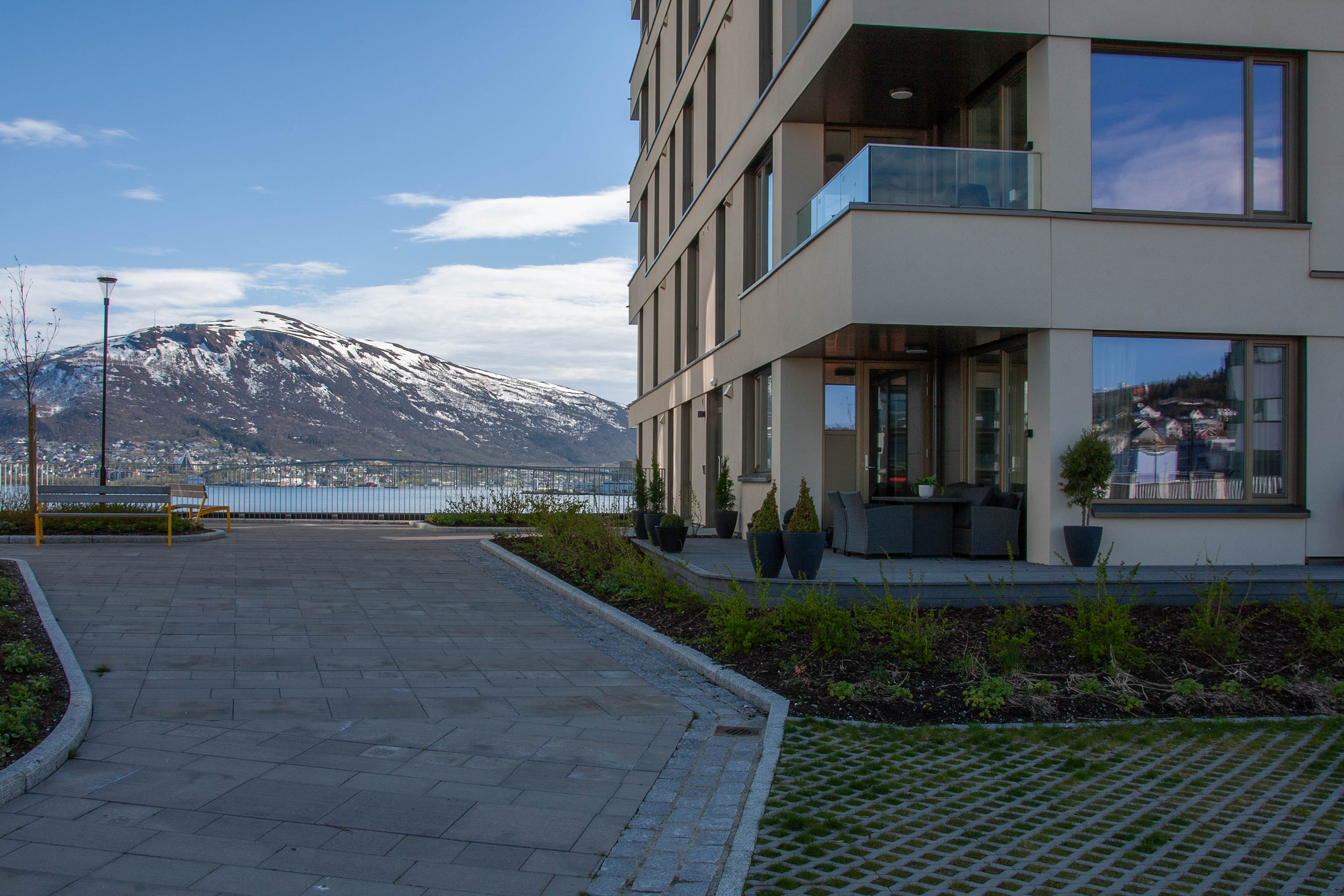 Uteområdet ved Alfon B med sitteplasser, og utsikt mot fjell og sjø.