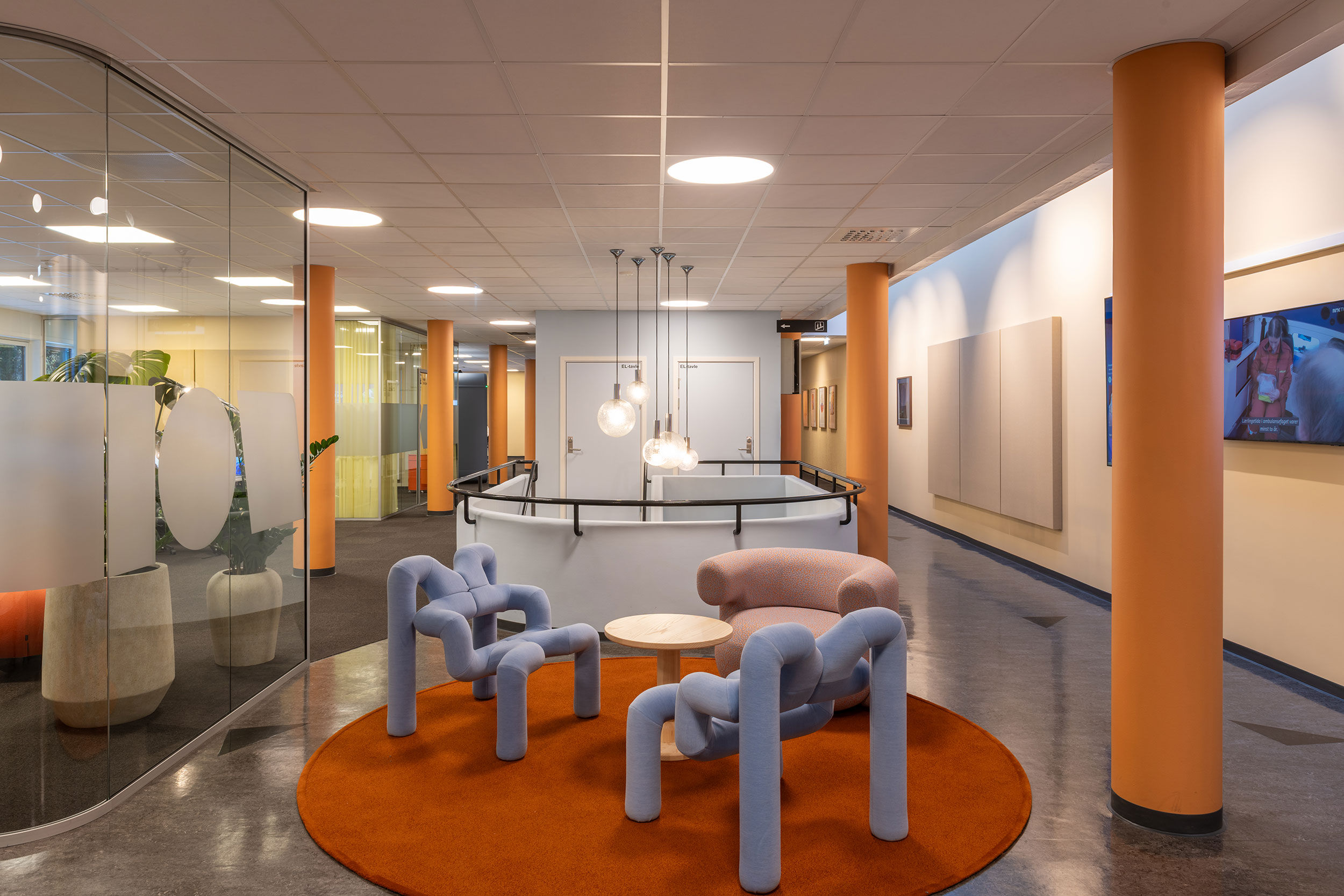 Interiørbilde fra fellesområde i NRK Tromsø med bord stoler og søyler som er fargerike.