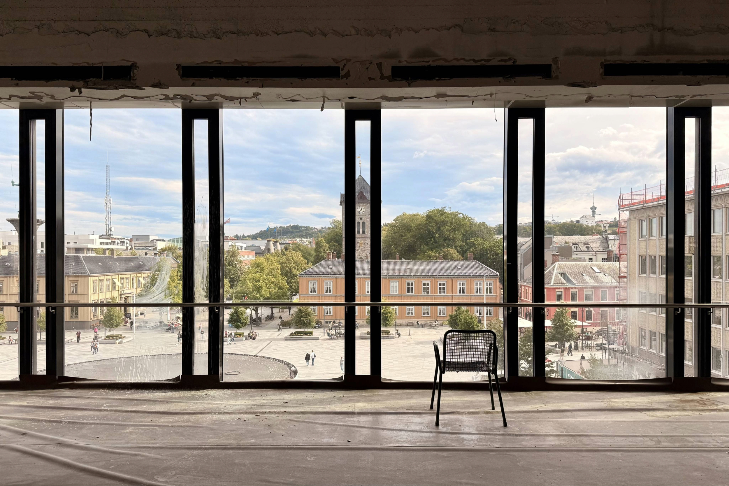 Utsikt fra et lokale under rehabilitering ved Trondheim Torg, der Asplan Viak bidrar i prosjektet, med store vindusflater mot torget og Trondheim sentrum.