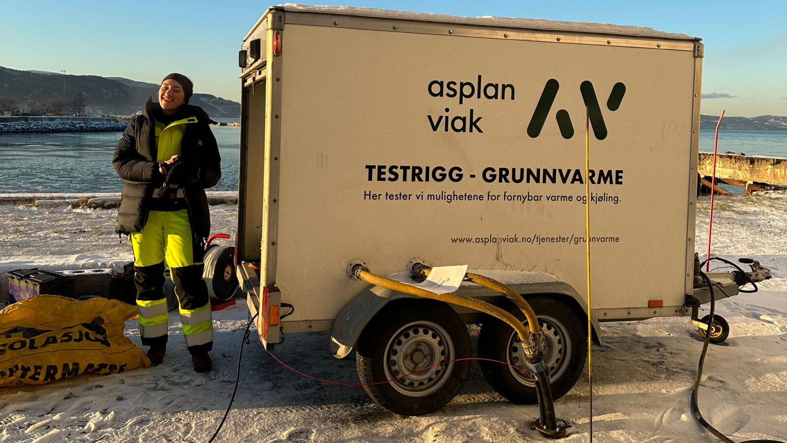 En person i arbeidsdress som viser maskiner som brukes for å legge bergvarme.