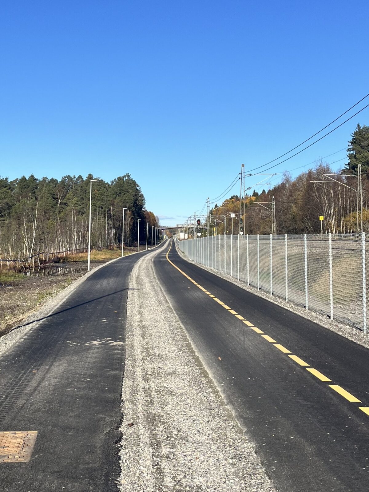 Gang- og sykkelvei mellom Ås sentrum og Hauger bru med fortau, grussti for løping og toveis sykkelvei markert med gul stripe.