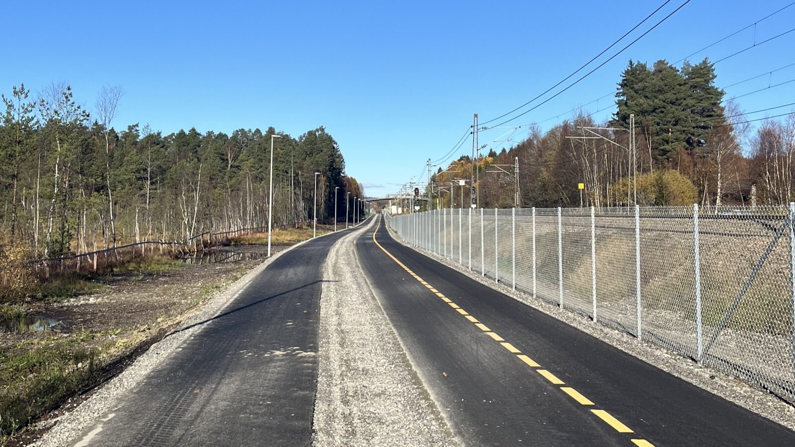 Gang- og sykkelvei mellom Ås sentrum og Hauger bru med fortau, grussti for løping og toveis sykkelvei markert med gul stripe.