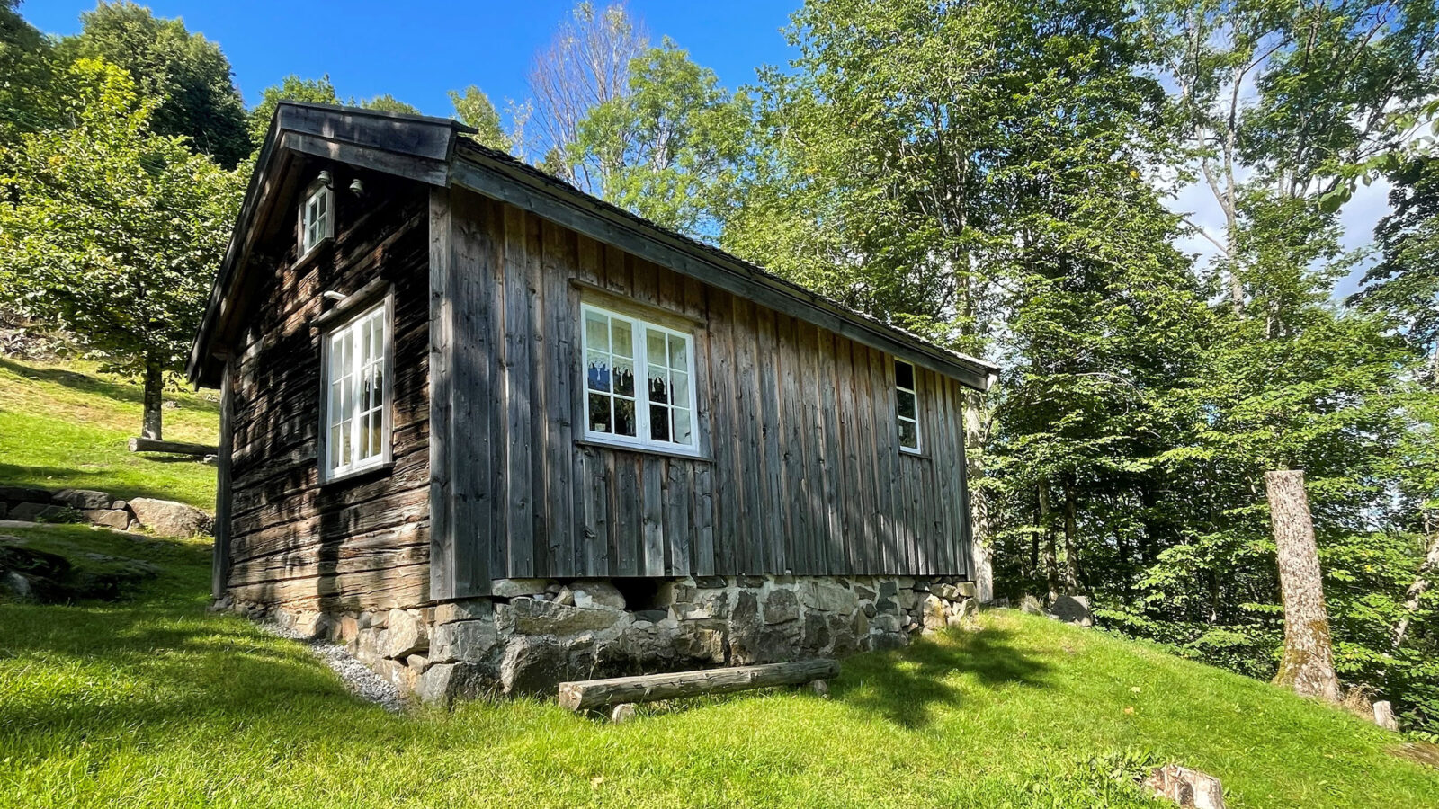 Et gammelt bygg på en husmannsplass på landet med trær rundt. som eksempel på kulturminne.