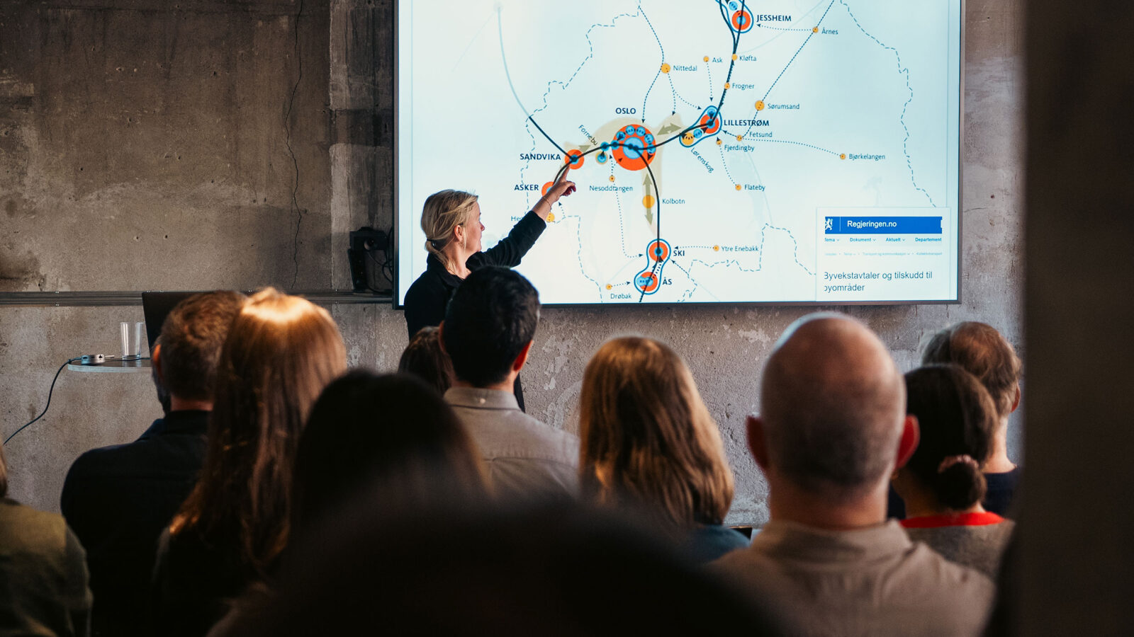 Foredragsholder peker på kartet under foredrag om bærekraftig mobilitet.