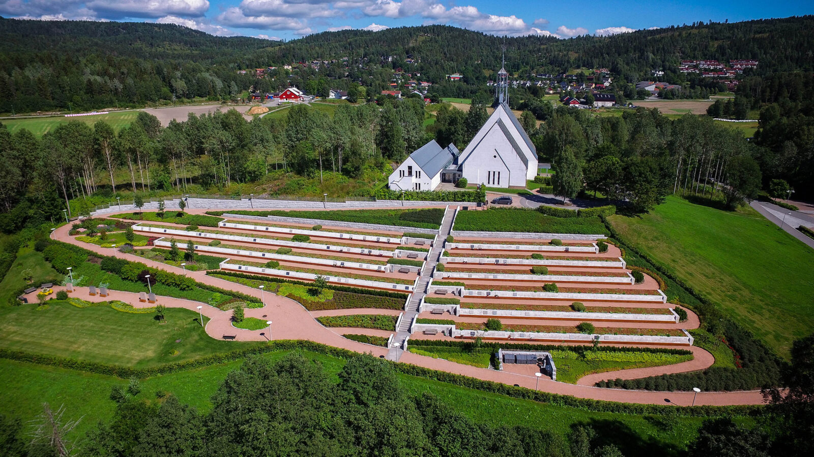 Dronebilde tatt skrått ovenfra av Lommedalen kirke og gravlund
