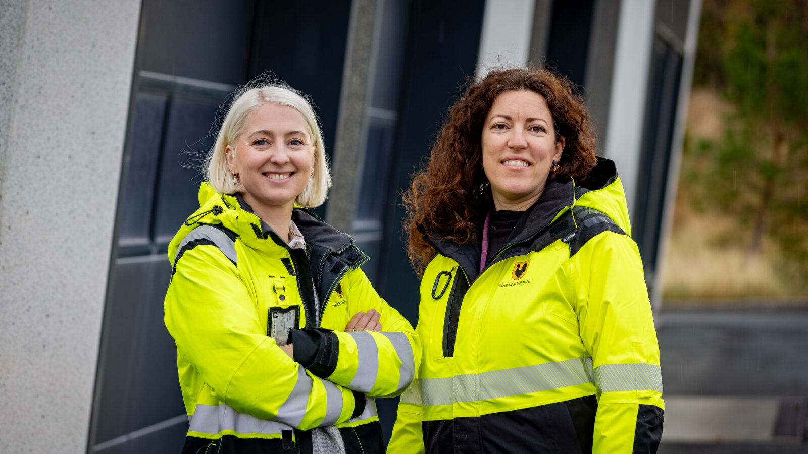 To kvinner står utendørs foran et bygg i ytterjakker som viser at de jobber i Malvik kommune.