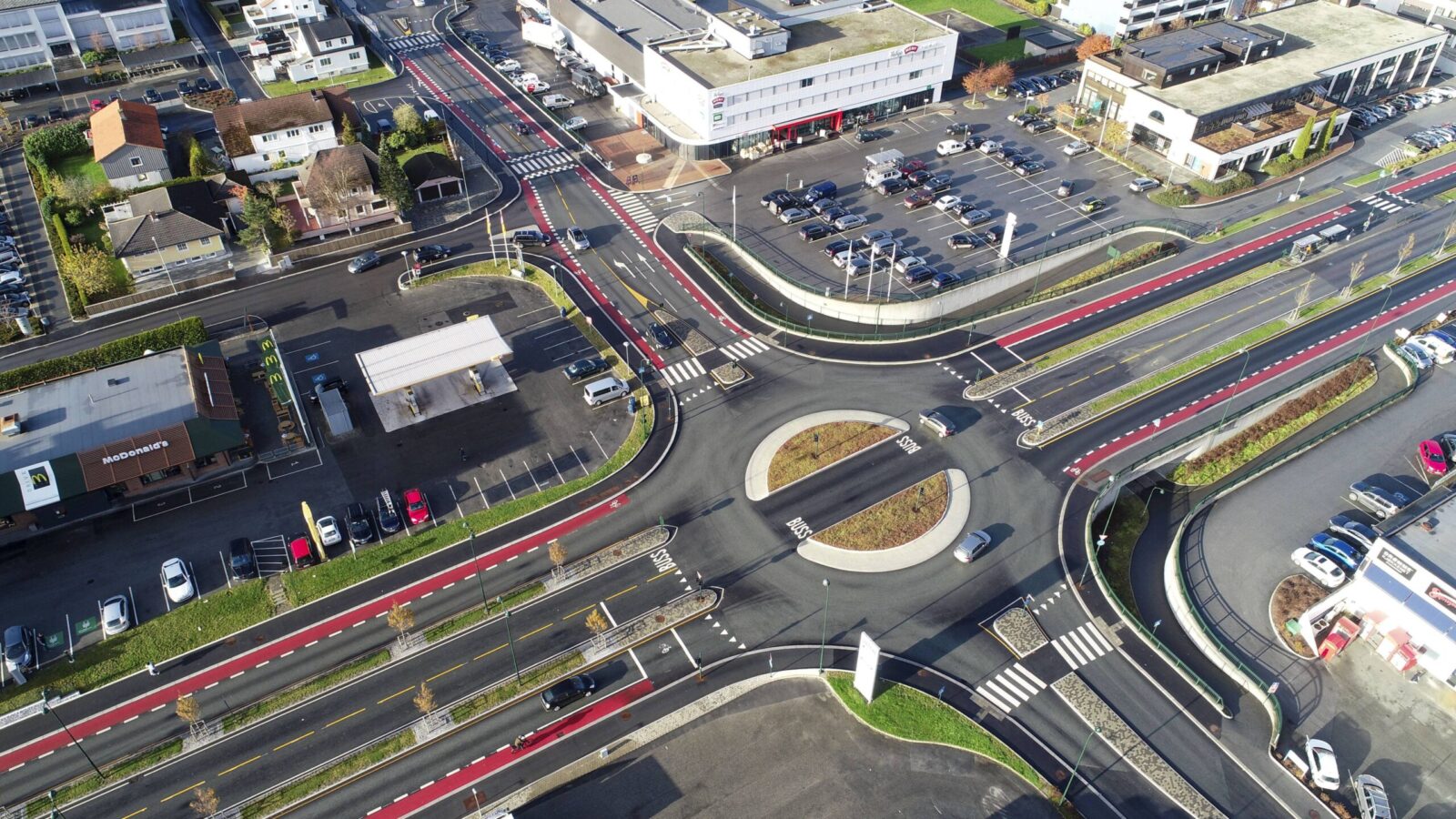 An oblique aerial drone view of a road junction with a roundabout.